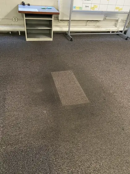 The same taped rectangle cleaned, sitting bright against the soiled carpet around it
