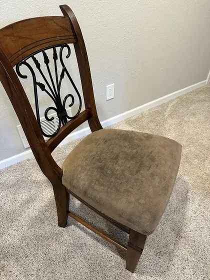 Wrought iron back dining chair with a mottled soiled fabric seat