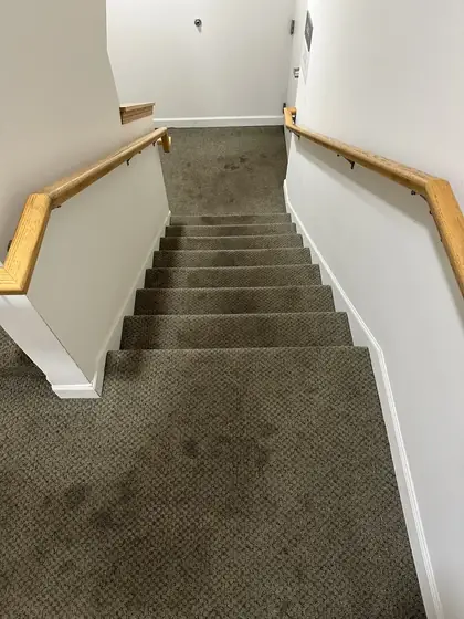 Carpeted staircase and landing with dark traffic soiling before cleaning